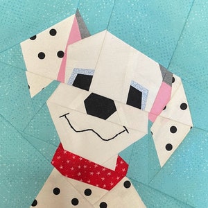 Puede incluir: Un cachorro dálmata blanco y negro con orejas rosas y un pañuelo de lunares rojos y blancos. El cachorro está hecho de tela y es parte de un bloque de colcha.