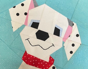 Puede incluir: Un cachorro dálmata blanco y negro con orejas rosas y un pañuelo de lunares rojos y blancos. El cachorro está hecho de tela y es parte de un bloque de colcha.