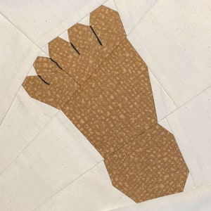 May include: A brown fabric foot-shaped patch with black stitching. The fabric has a speckled pattern.