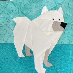 May include: A white paper pieced polar bear on a turquoise background with a swirling pattern. The bear is standing on a turquoise background with a grid pattern.