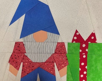 May include: A red and white polka dot gift box with a green bow is next to a gnome with a blue hat, a white beard, and a red and white polka dot shirt.