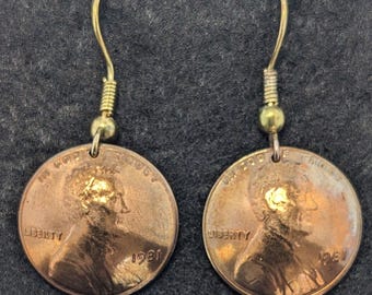 Könnte beinhalten: Ein Paar goldfarbene Ohrringe mit einem US-Penny aus dem Jahr 1981 an jedem Ohrring. Die Ohrringe sind mit einem einfachen Drahtbügel gefertigt.