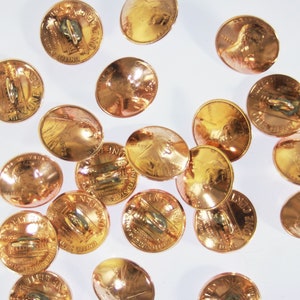 Op de afbeelding: Een verzameling van 17 gouden metalen knopen, elk met een ontwerp van een penny met het profiel van Abraham Lincoln aan de ene kant en het Lincoln Memorial aan de andere kant.