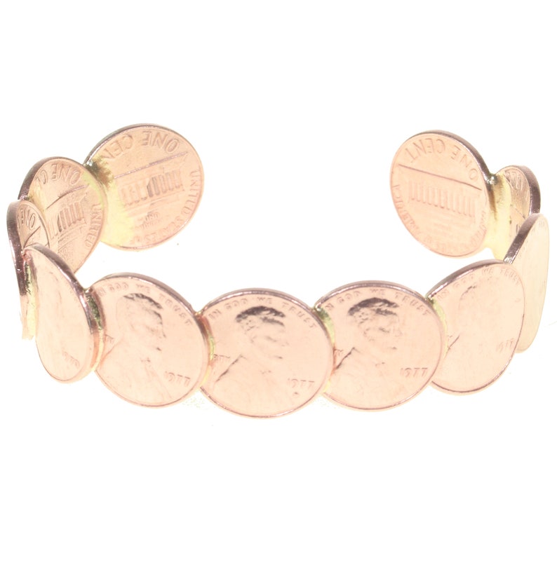 Peut inclure: Un bracelet manchette de couleur cuivr&eacute;e fait de pi&egrave;ces de monnaie am&eacute;ricaines. Le bracelet est ouvert aux extr&eacute;mit&eacute;s et comporte une s&eacute;rie de pi&egrave;ces de monnaie reli&eacute;es entre elles. Les pi&egrave;ces montrent le profil d'Abraham Lincoln et l'ann&eacute;e 1977.