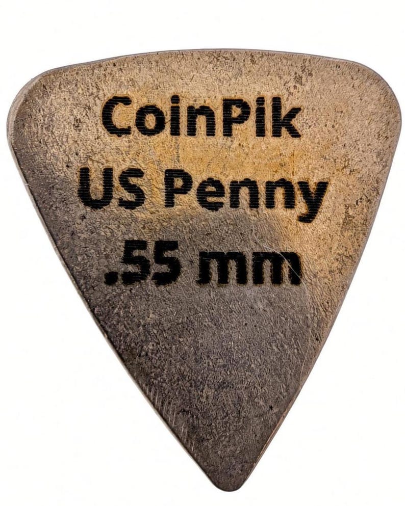 K&ouml;nnte beinhalten: Ein dreieckiges Gitarrenplektrum aus einem kupferfarbenen US-Penny mit strukturierter, metallischer Oberfl&auml;che. Der Text CoinPik, US Penny und .55 mm ist schwarz auf die Vorderseite graviert und gibt Material und St&auml;rke an.