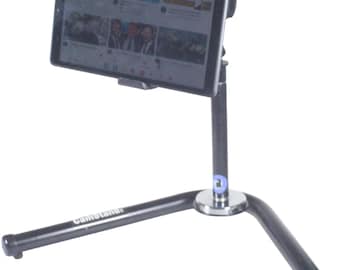 Puede incluir: Un soporte de tableta negro con una base de trípode. El soporte tiene un brazo de metal que se extiende hacia arriba y sostiene una tableta en posición horizontal. La tableta muestra un video de YouTube.