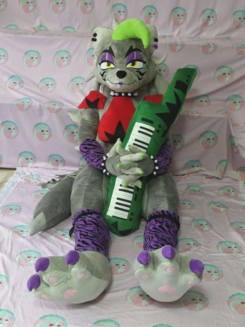 May include: A large gray plush toy with purple and black striped leggings, green hair, and purple claws. The toy is holding a green keyboard.