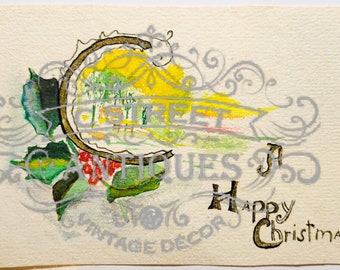 May include: Vintage Christmas card with a watercolor design. The card features a central circular image with a landscape scene, surrounded by holly and berries. The words "Happy Christmas" are written in a decorative font.