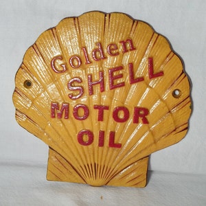 May include: A yellow cast iron shell-shaped sign with the words "Golden Shell Motor Oil" in red lettering.