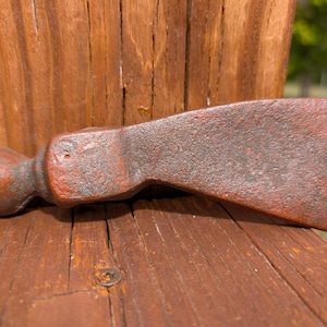 May include: A rusted iron tomahawk head featuring a rounded poll and a wide, flat blade edge. The metal surface displays a textured, weathered patina with deep reddish-brown oxidation throughout the entire body of the tool head.