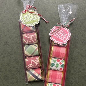 May include: Two clear cellophane bags filled with small wrapped chocolates. Each bag has a red and green patterned tag that says "Have a Holly Jolly Christmas".