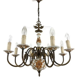 Pode incluir: Um candeeiro de teto branco e dourado com oito luzes. O candeeiro de teto tem um design floral e um pássaro no topo.
