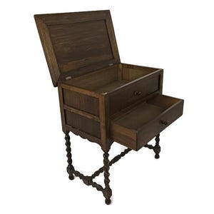 Puede incluir: Un cofre de madera con una tapa con bisagras y un cajón. El cofre está sostenido por cuatro patas retorcidas. El cofre está hecho de madera oscura y tiene un aspecto rústico.