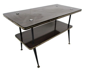May include: A two-tiered, mid-century modern side table. The table has a dark brown wood grain finish with gold trim and black legs. The top tier has two silver-colored accents.