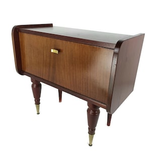 Op de afbeelding: Een donkerhouten bijzettafel met een lade en vier taps toelopende poten. De lade heeft een messing handgreep.