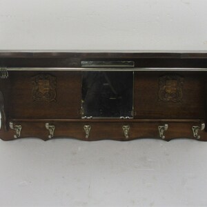 May include: A dark wood wall-mounted coat rack with a shelf, mirror, and coat hooks. The rack has a metal bar for hanging clothes and decorative crests either side of the mirror. The date 14/01/2020 is visible in the bottom right corner.
