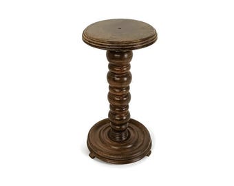 May include: A dark brown, wooden plant stand with a round top and base. The stand's central column features a series of rounded, bulbous shapes. The stand is approximately 71 cm tall.