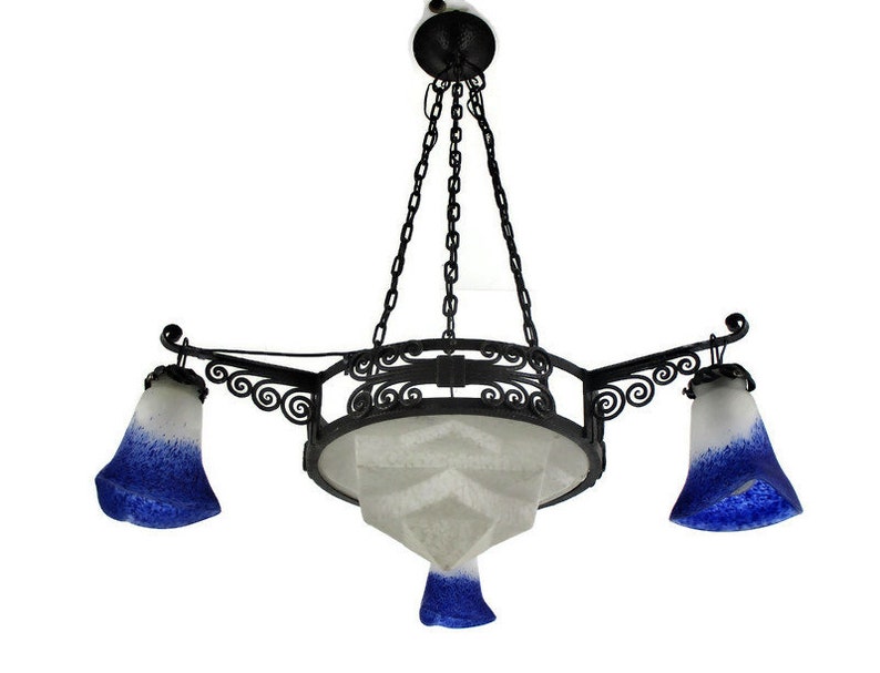 May include: An antique chandelier with a black metal frame and three bell-shaped shades. The shades are white with a blue gradient. The central shade is a geometric shape. The fixture hangs from a chain.