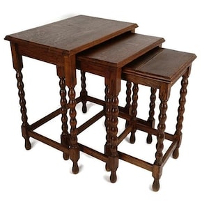 Può includere: Set di tre tavolini a incastro antichi in legno marrone scuro. Ogni tavolo ha un piano rettangolare e gambe tornite. I tavoli sono progettati per essere riposti uno dentro l'altro.