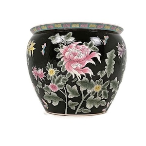 以下が含まれることがあります： ピンクと白の菊、緑の葉、蝶が描かれた花柄の黒いセラミックプランター。プランターは金色の縁取りが施されています。
