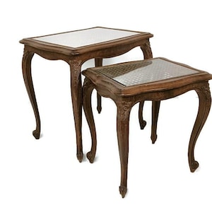 Può includere: Due tavolini a incastro antichi con cornici in legno marrone scuro e gambe ornate e curve. I piani dei tavoli presentano una superficie chiara a motivi, probabilmente in vetro. I tavoli sono di diverse dimensioni, progettati per incastrarsi.