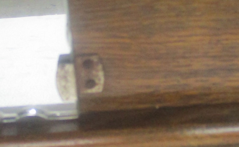 May include: Close-up of a wooden furniture joint with a metal hinge. The wood grain is visible, and the hinge has two holes. The image is well-lit, highlighting the details of the construction.