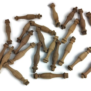 Puede incluir: Una colección de 20 husos de madera, cada uno con un diseño torneado y una base cuadrada. Los husos son de color marrón claro y están dispersos sobre un fondo blanco.