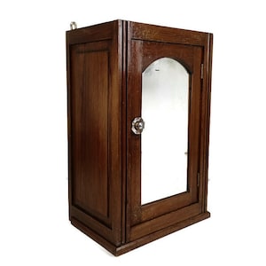 May include: A dark brown wooden cabinet with a mirrored door and a small metal knob. The cabinet has a simple design and is perfect for storing small items.