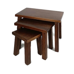 May include: A set of three wooden nesting tables in a dark brown finish. The tables are square and have a simple design.
