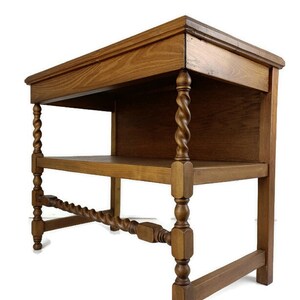 May include: A wooden table with a shelf and twisted legs. The table is made of dark wood and has a simple design.