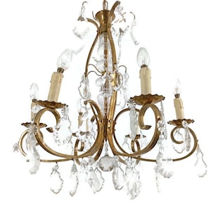 Op de afbeelding: Een vintage gouden kroonluchter met zes kaarsvormige lampen en heldere kristallen accenten. De sierlijke armatuur heeft gebogen armen en decoratieve kristallen hangers, waardoor een elegant en klassiek verlichtingsstuk ontstaat.