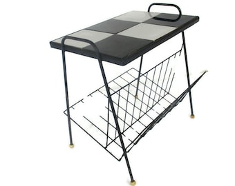 Puede incluir: Una mesa auxiliar de mediados de siglo con una tapa a cuadros blancos y negros y una estructura de metal negro. Tiene un revistero incorporado y patas de color latón. La mesa mide aproximadamente 61 cm de largo, 41 cm de ancho y 51 cm de alto.