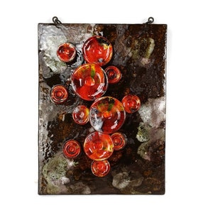 May include: A ceramic wall art piece with a brown background and red, orange, and yellow circles. The circles are raised and have a textured surface.