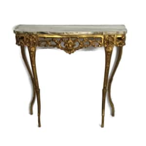 Può includere: Una consolle dorata con piano in marmo. Il tavolo presenta dettagli ornati e intagliati sul grembiule e sulle gambe. Le gambe sono curve e sottili, aggiungendo all'elegante design del tavolo. Il piano in marmo ha un motivo grigio chiaro e bianco.