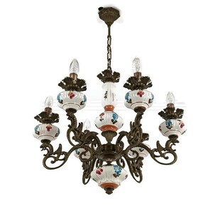 Könnte beinhalten: Ein verzierter Kronleuchter mit acht Lichtern. Die Leuchte hat eine Bronzefinish mit weißen Keramikakzenten mit floralen Designs in Rot, Blau und Orange. Die Glühbirnen sind klar und flammenförmig.