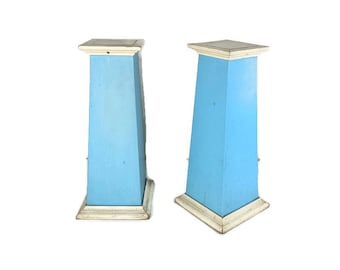 Könnte beinhalten: Zwei blaue und weiße Podestständer mit quadratischer Oberseite. Die Ständer sind aus Holz und haben ein schlichtes Design.
