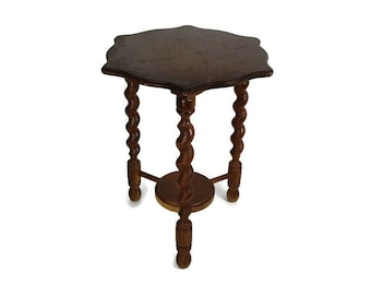 May include: A dark brown wooden table with a scalloped top and twisted legs. The table has a round lower shelf.