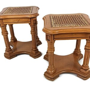 May include: Two wooden end tables with a woven cane top. The tables have a square top with rounded edges and four legs with a fluted design.