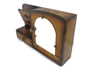 May include: A vintage-style wooden desk organizer with a warm brown finish. It features a drawer, a slot for papers, and a large arched opening. The organizer has decorative hardware and a classic design.