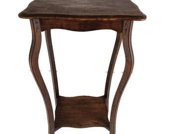 Puede incluir: Una mesa auxiliar de estilo antiguo, de color marrón oscuro, con una parte superior cuadrada y un estante inferior. La mesa tiene patas curvas y un acabado envejecido, lo que le da un aspecto vintage. La mesa mide unos 71 cm de alto.