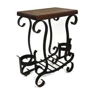 Può includere: Un portavasi in metallo nero con un ripiano superiore in legno e decorazioni a volute. Il portavasi ha un ripiano inferiore con un motivo a griglia.