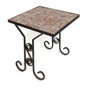 Op de afbeelding: Vierkante bijzettafel met een mozaïektegelblad in roze, beige en bruine tinten. De tafel heeft een smeedijzeren frame met decoratief krulwerk en is ongeveer 50 cm breed en 50 cm lang.