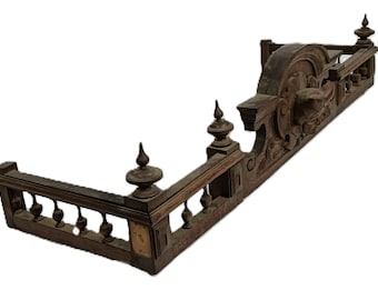May include: Ornate, dark brown fireplace mantel with decorative carvings and finials. The mantel features a balustrade design along the front and a detailed central panel. A classic piece for home decor.