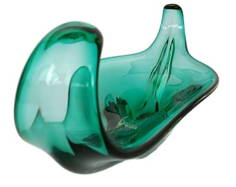 May include: A teal-colored, abstract glass bowl with a unique, flowing design. The bowl features a curved, open shape with a raised, pointed element on one side. The glass has a glossy finish, and the overall aesthetic is modern and artistic.