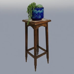 May include: A tall, dark brown wooden plant stand with four slender legs and a square top. A deep blue ceramic pot sits on the surface, containing a trailing green succulent plant with long, cascading stems and a small, rosette-shaped succulent.