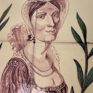 Puede incluir: Un azulejo vintage que representa a una mujer con un tocado de encaje blanco y un vestido marrón con un collar de perlas. El azulejo tiene un fondo crema con un diseño de hojas verdes.