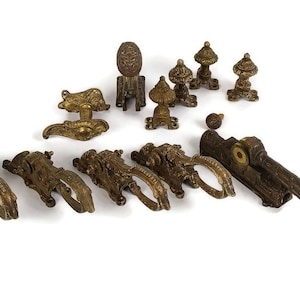 Può includere: Una collezione di ferramenta per finestre in ottone antico, tra cui chiusure, cerniere e un pezzo decorativo. La ferramenta è in vari stili e dimensioni, con dettagli intricati e una patina usurata.