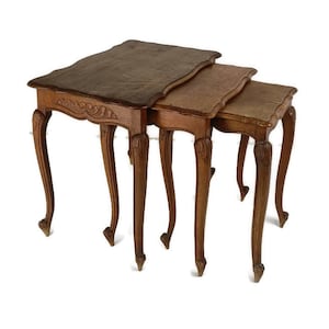 May include: A set of three nesting tables with intricate carved details on the legs and tops. The tables are made of wood and have a rich brown finish.