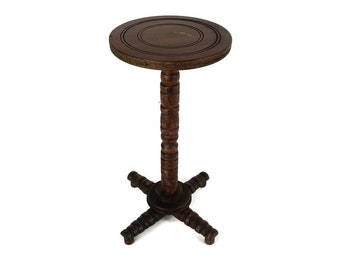 May include: A dark brown wooden side table with a round top and a turned pedestal base. The table has four legs that are turned and flared at the bottom.