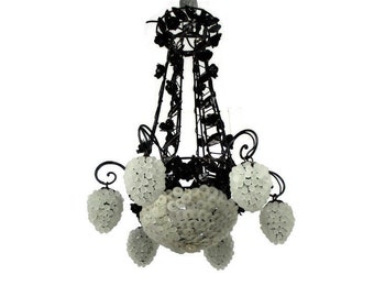 May include: A black wrought iron chandelier with frosted glass grapes. The chandelier has a grapevine design and is decorated with frosted glass grapes.